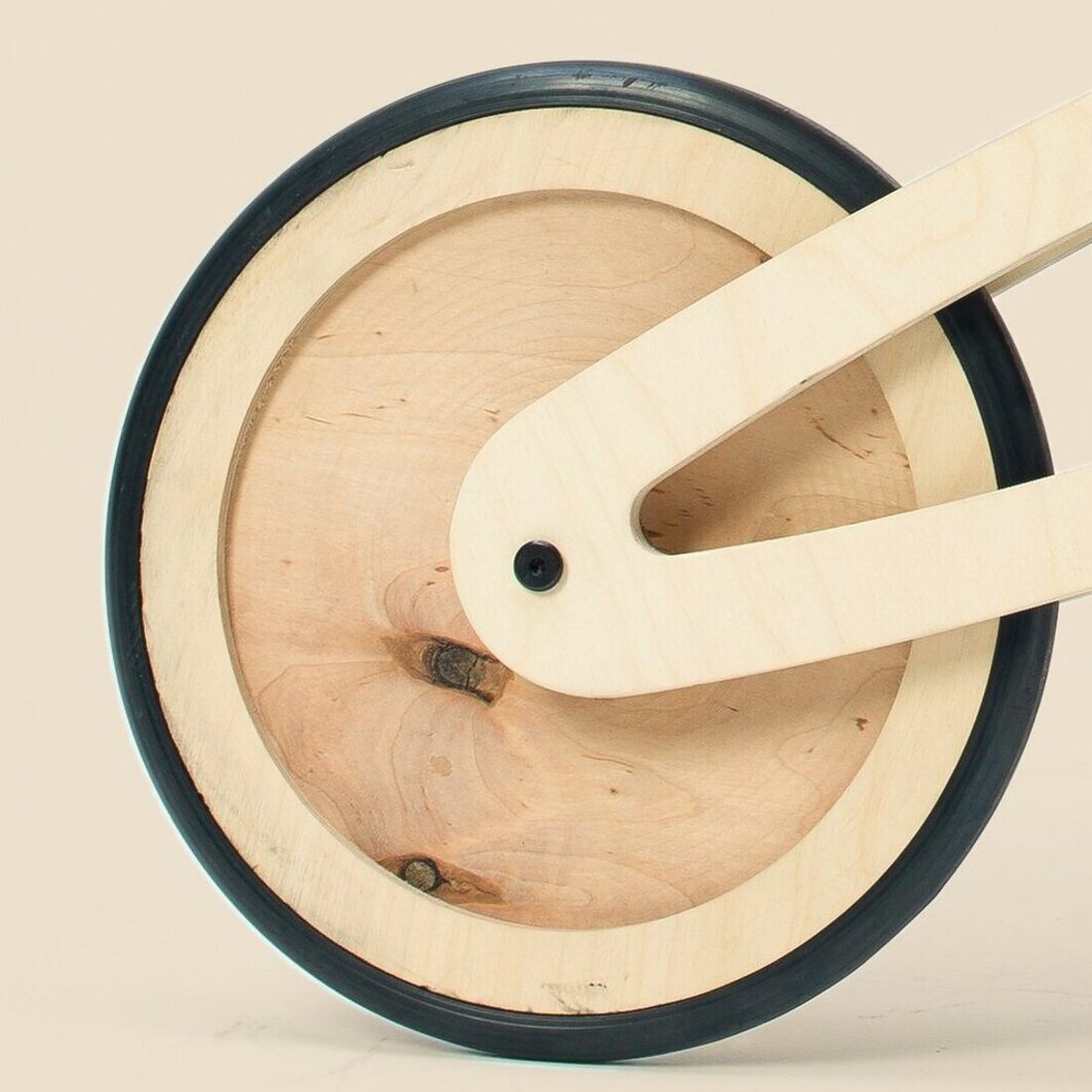 The wheel of a natural Tochak — bare birch plywood, grain and knots showing, inside a black rubber tire.